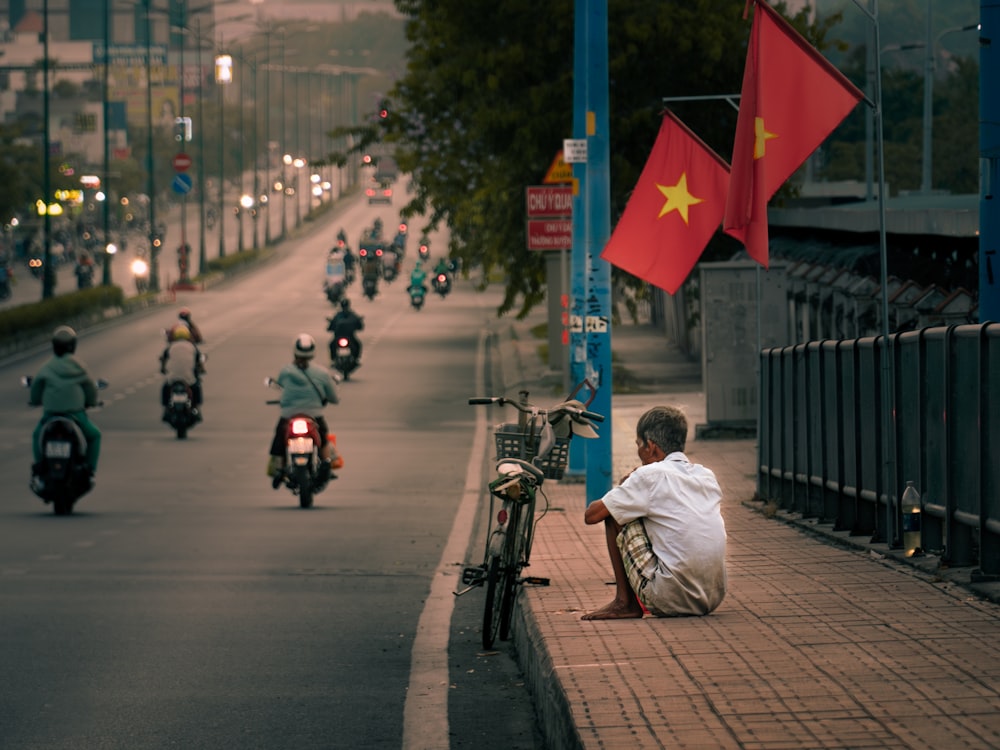 a man sitting on the side of a road next to a motorcycle