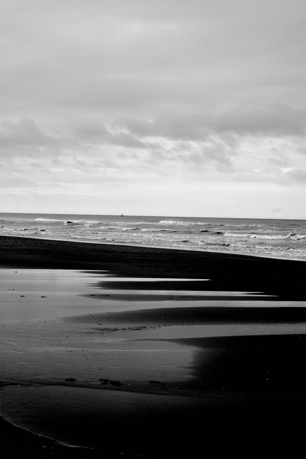 a black and white photo of a person walking on the beach