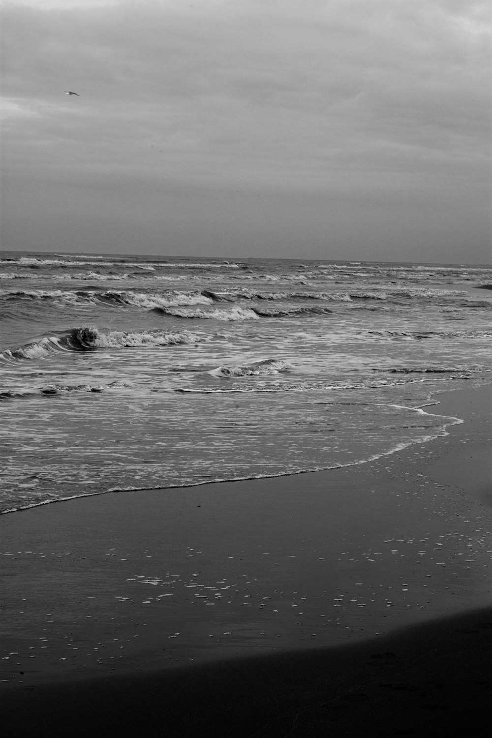 a black and white photo of a person walking on the beach