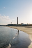 a beach with a light house in the distance