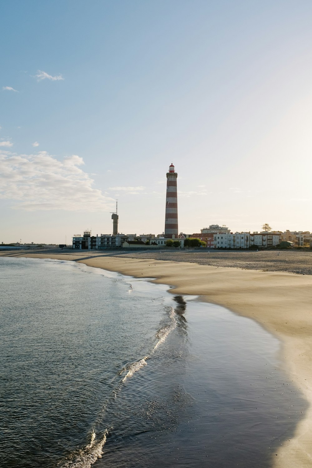 a beach with a light house in the distance