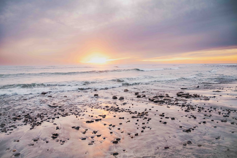 the sun is setting over the ocean on the beach