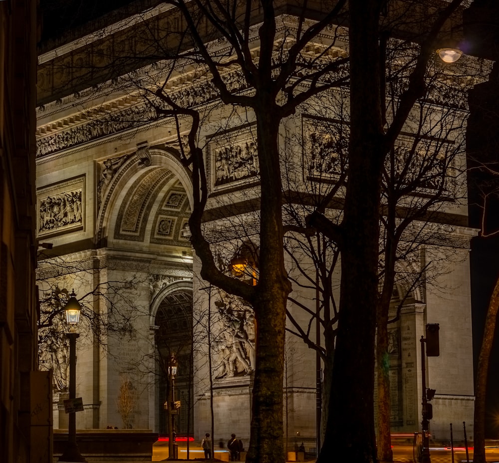 a building lit up at night with trees in front of it