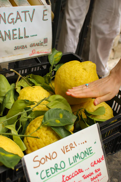 a person holding a lemon in front of a bunch of lemons