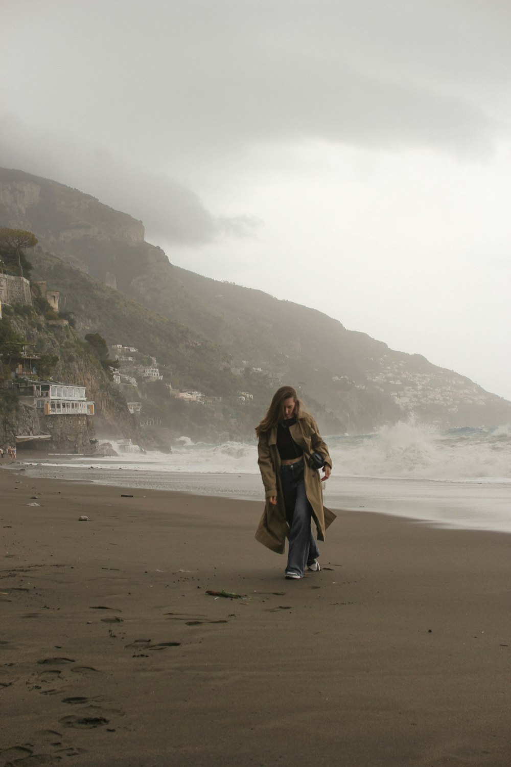 a woman walking on a beach next to the ocean