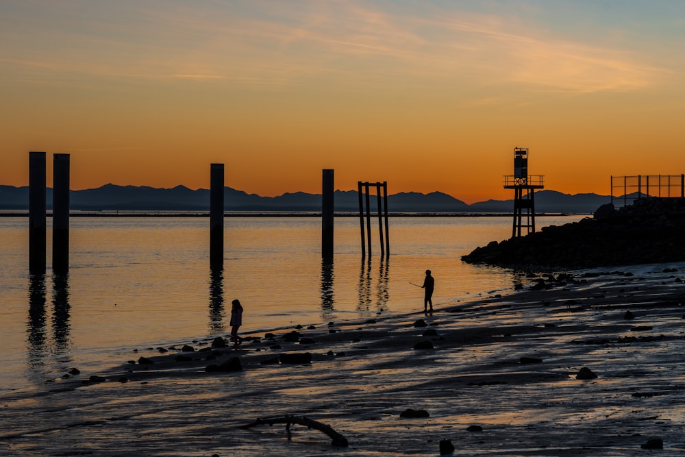 a couple of people standing on a beach next to the ocean