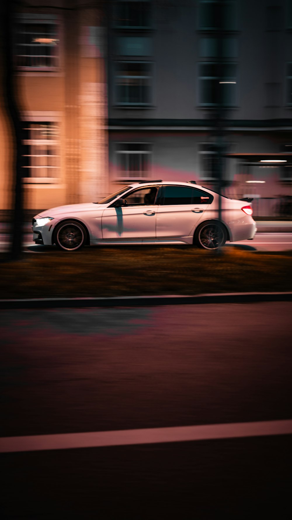 a white car driving down a street at night