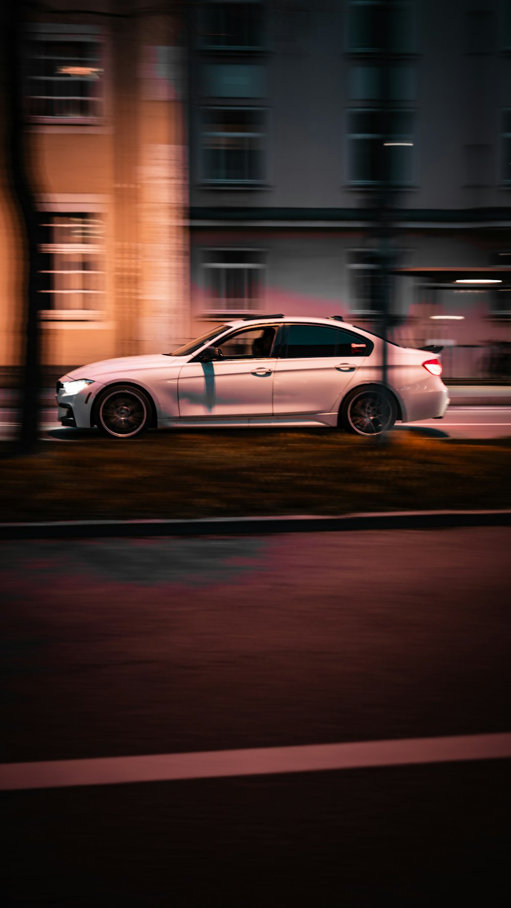 un coche blanco conduciendo por una calle de noche
