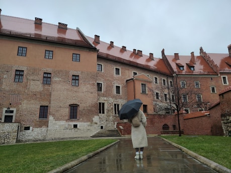 a woman holding an umbrella walking down a rain soaked walkway