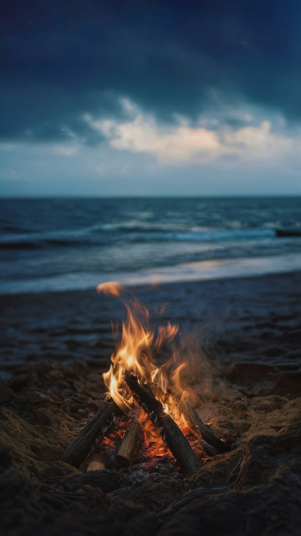 a campfire on a beach with the ocean in the background