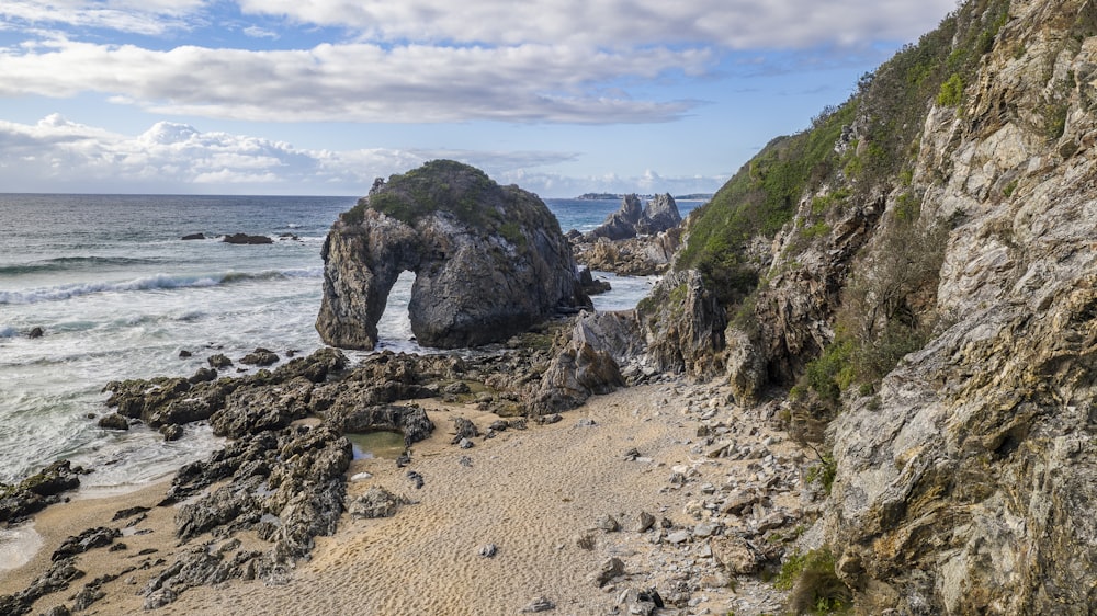 a rocky beach next to the ocean under a cloudy sky