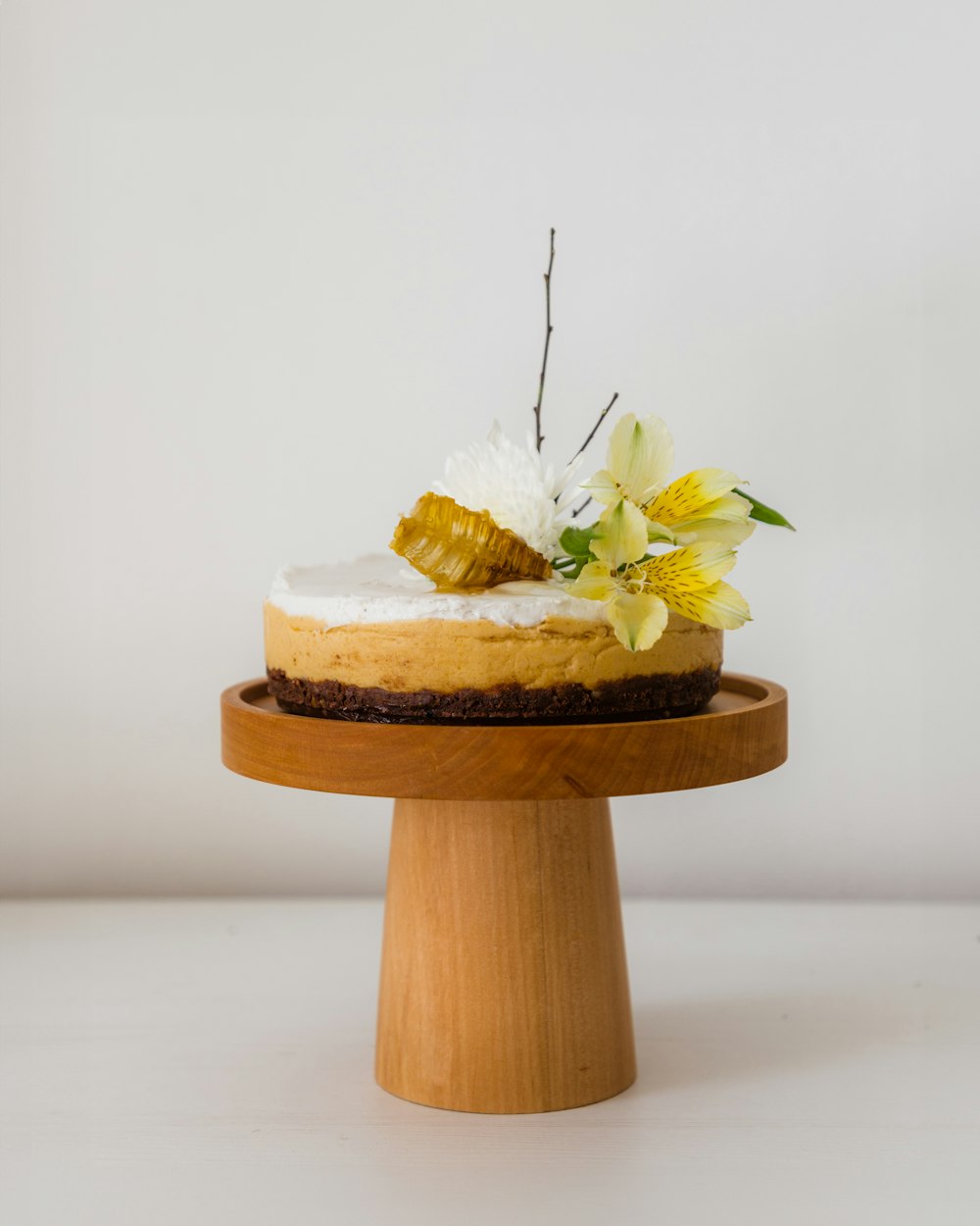 um bolo em um suporte de madeira com flores no topo