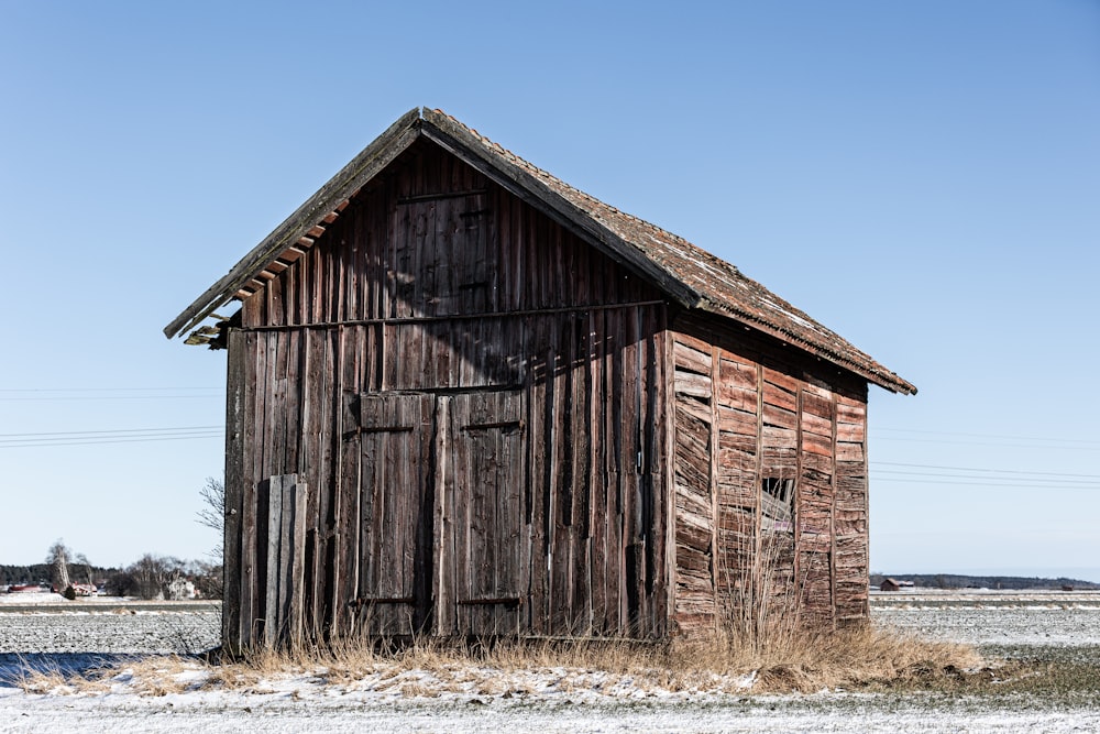 an old wooden building in the middle of a field