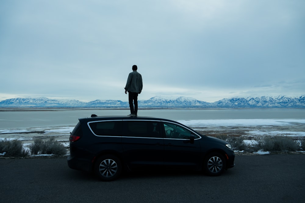 a man standing on top of a black car