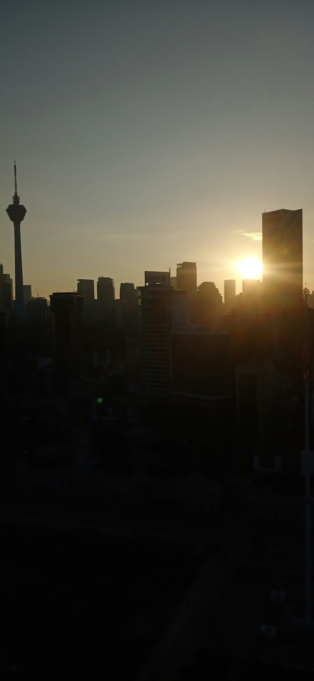 the sun is setting over a city with tall buildings