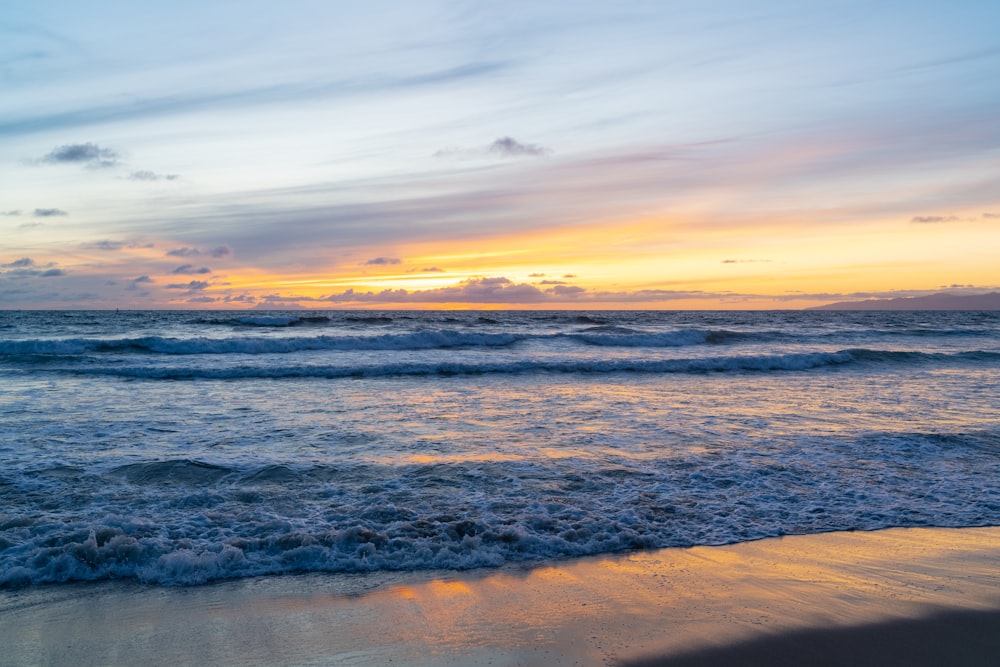 un coucher de soleil sur l’océan avec des vagues qui arrivent