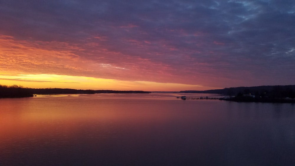 a sunset over a body of water with a boat in the distance