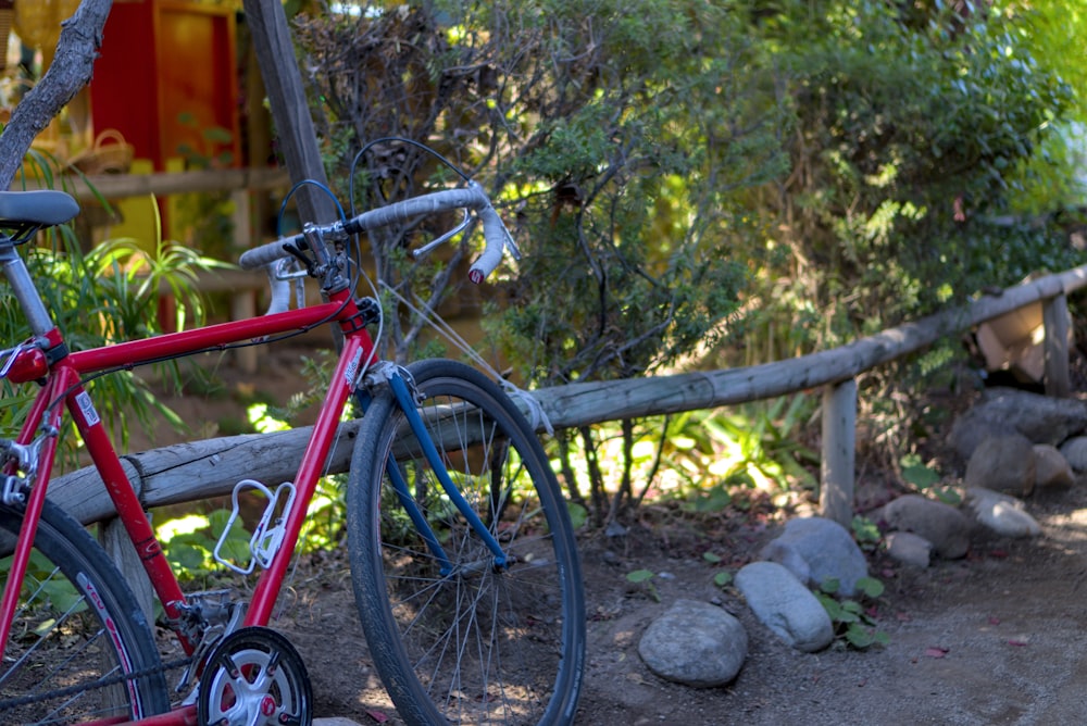 a red bike parked next to a wooden fence