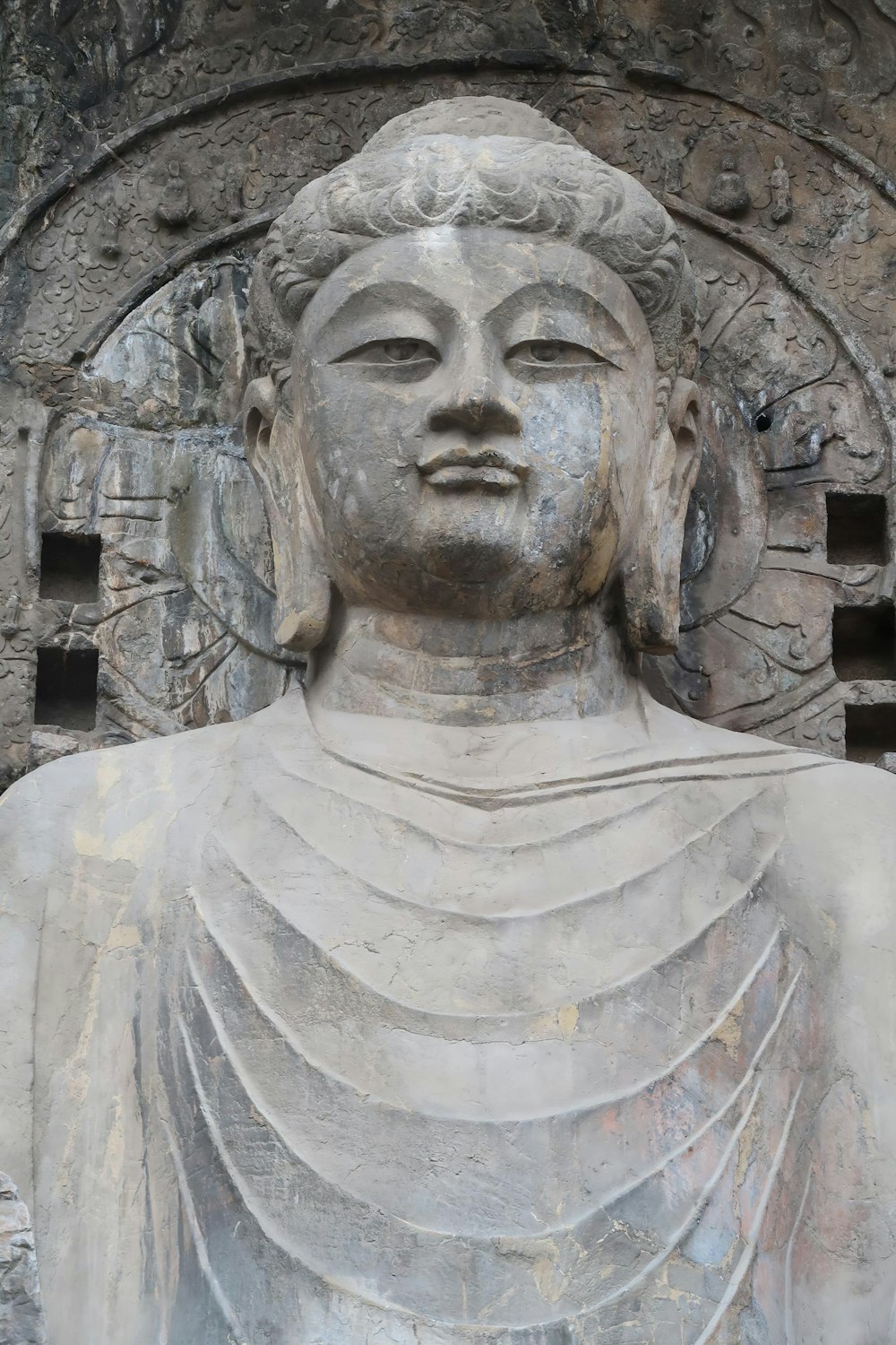 a statue of a buddha in front of a stone wall