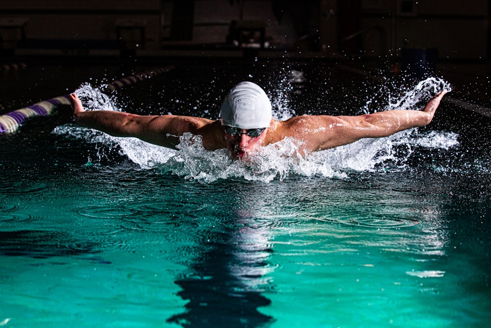 un hombre nadando en una piscina con un sombrero puesto
