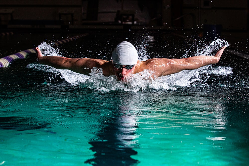 a man swimming in a pool with a hat on