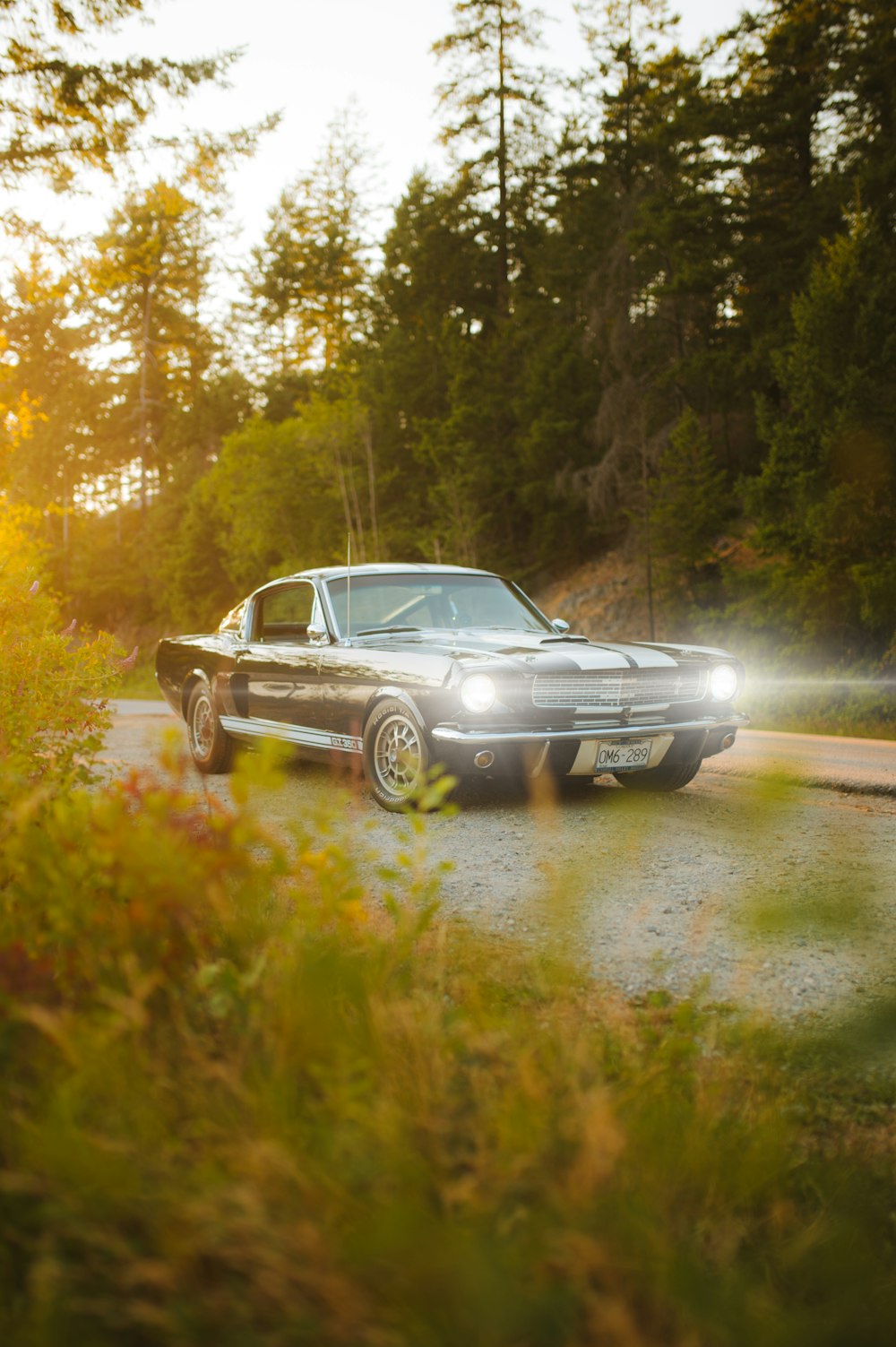 a classic car is parked on a gravel road