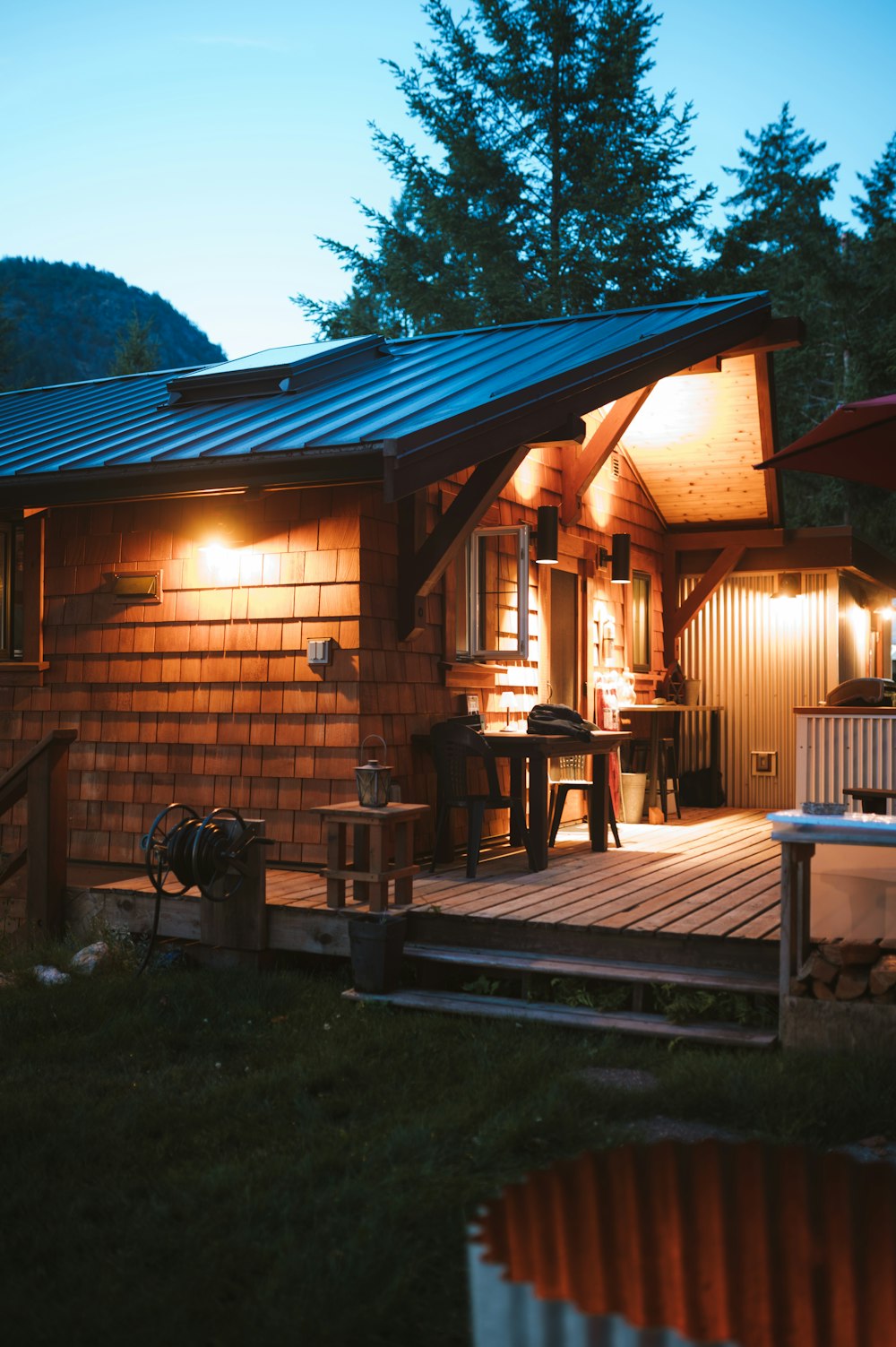 a small wooden cabin with a deck and lights on