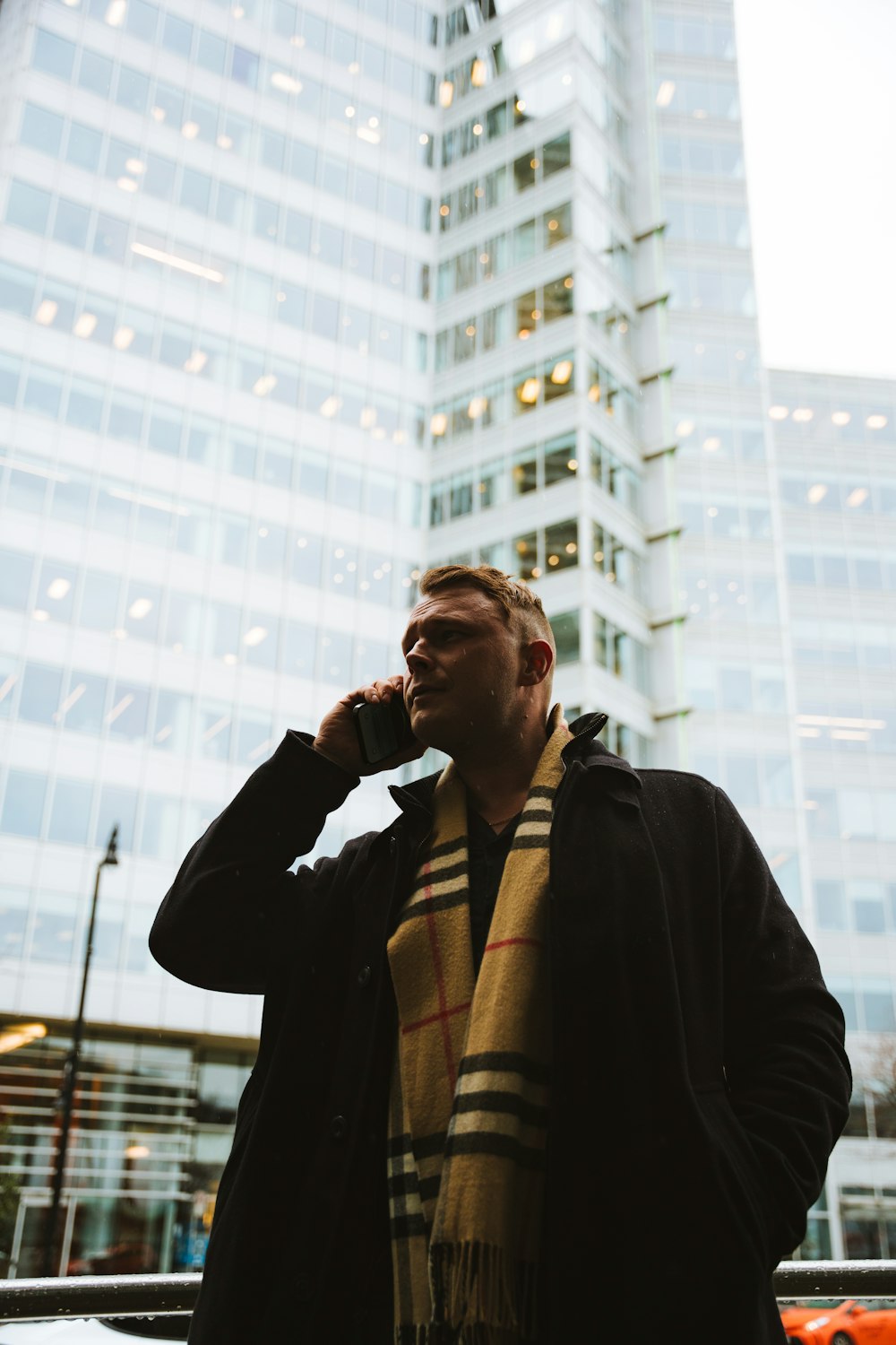 a man standing in front of a tall building talking on a cell phone