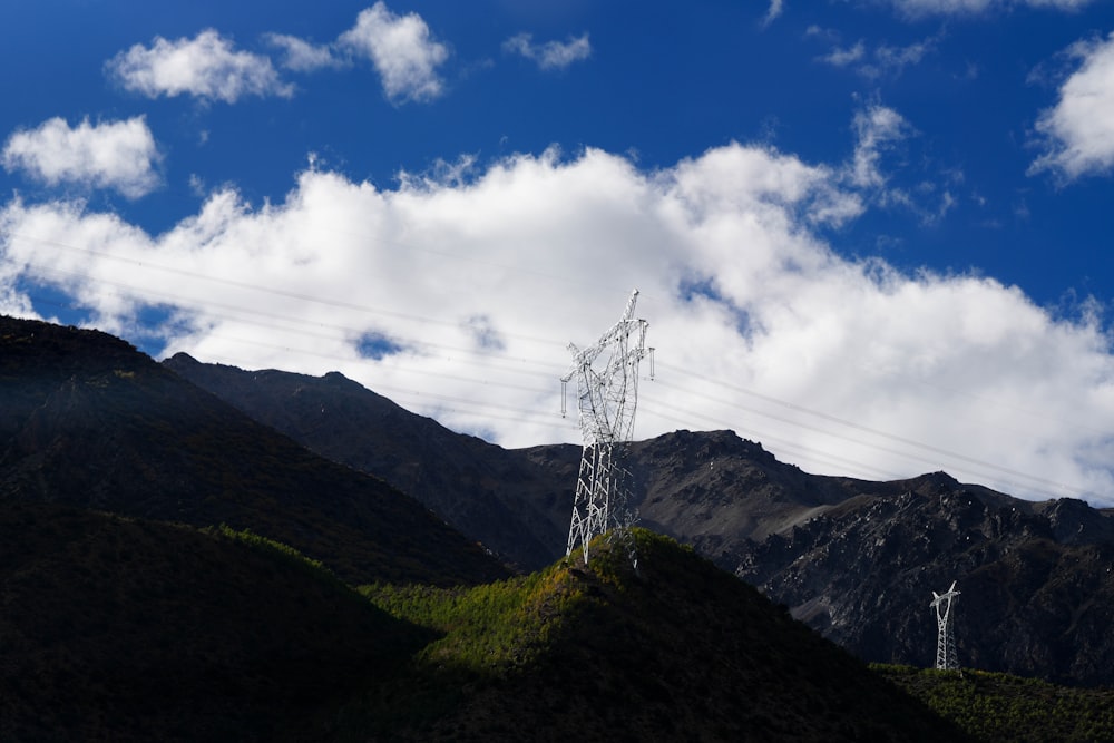 a telephone pole on a hill with mountains in the background