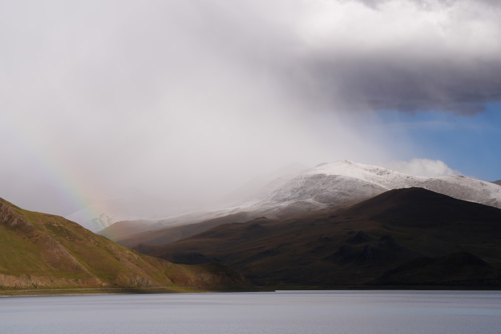 a rainbow in the sky over a mountain lake