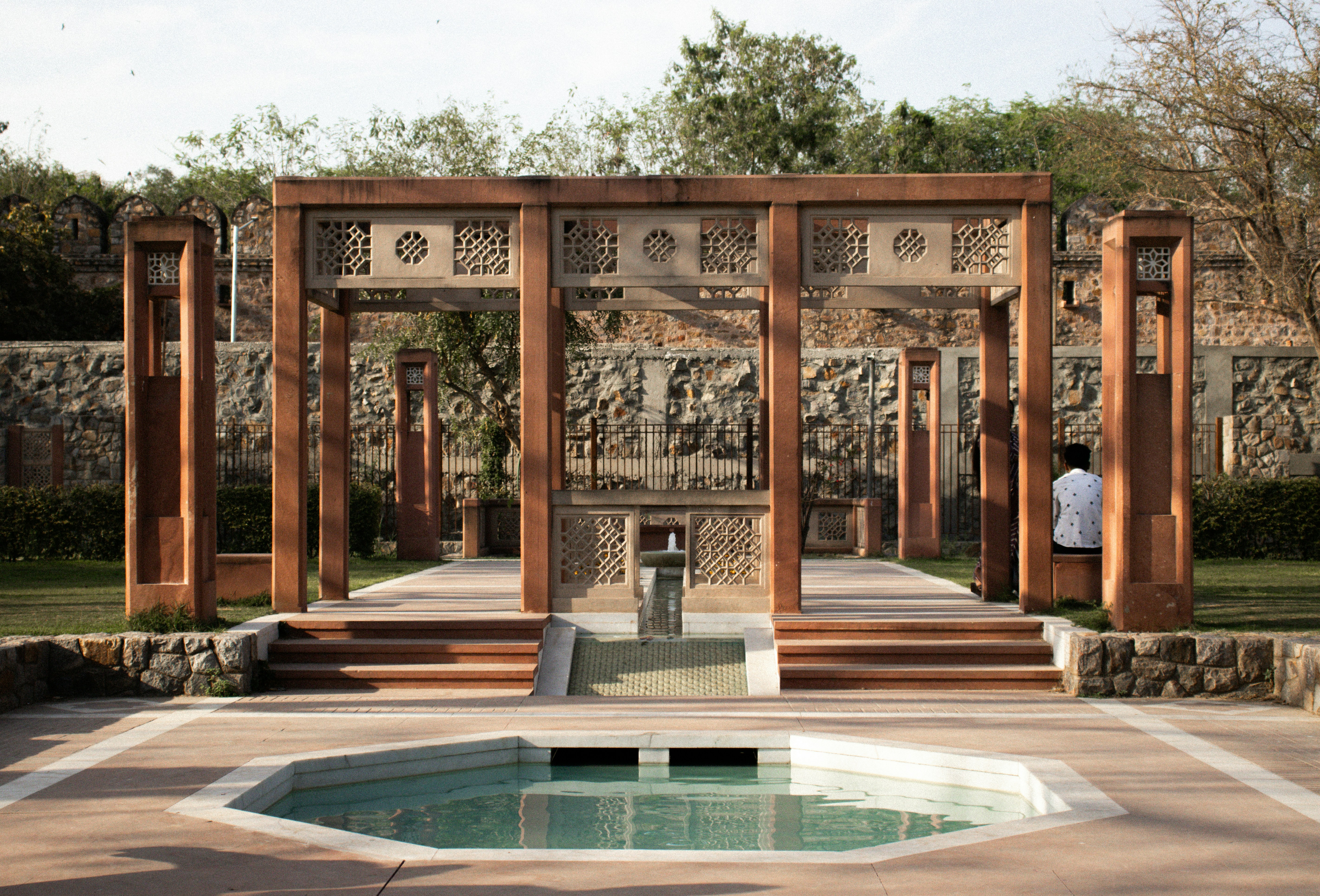 a man standing in front of a fountain in a park