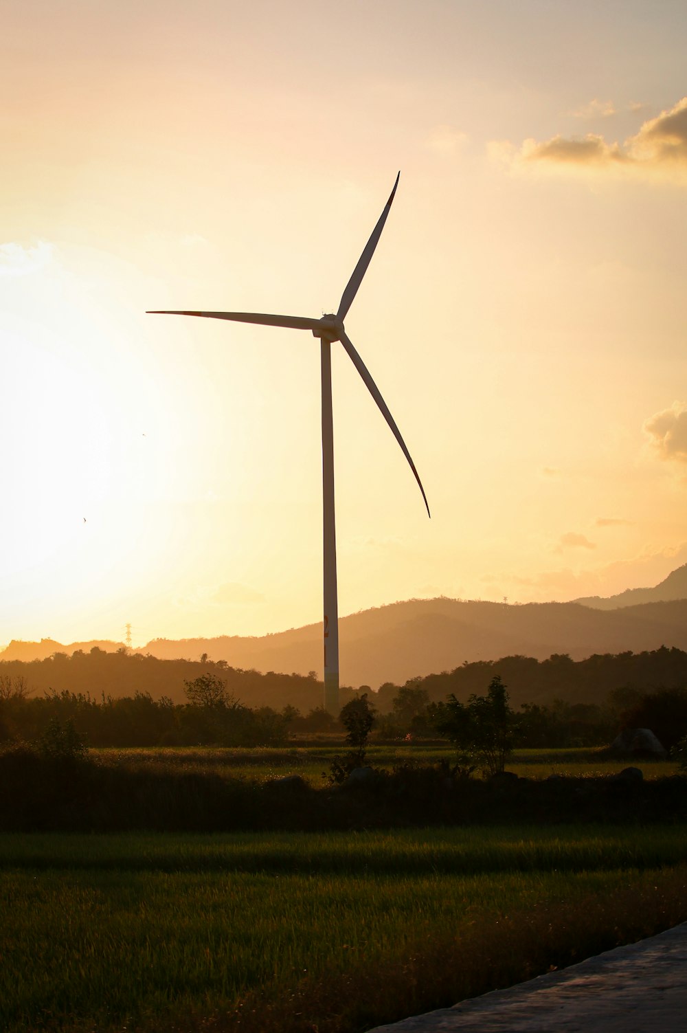 o sol está se pondo atrás de uma turbina eólica