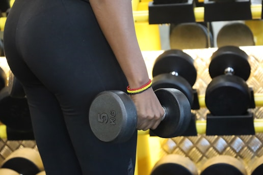 a woman holding two dumbs in a gym