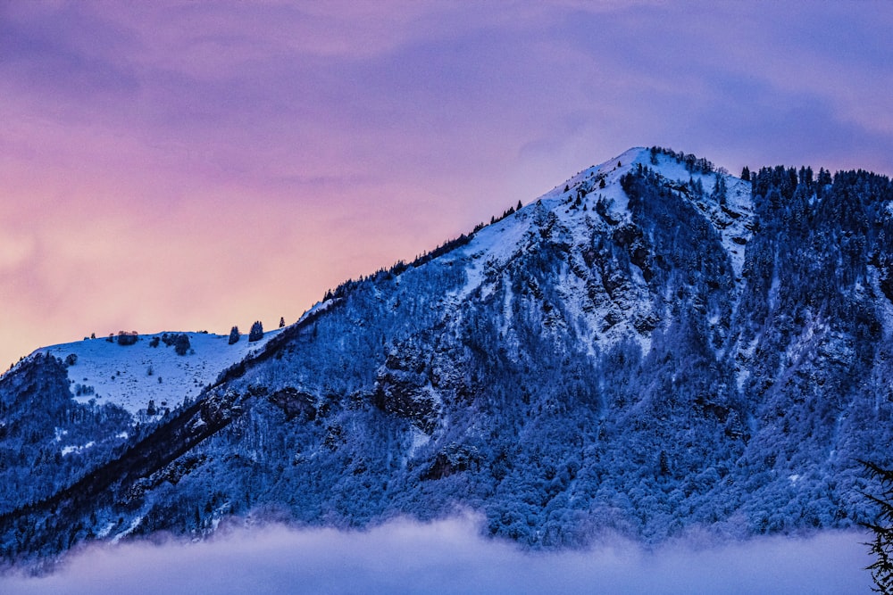 a mountain covered in snow under a purple sky