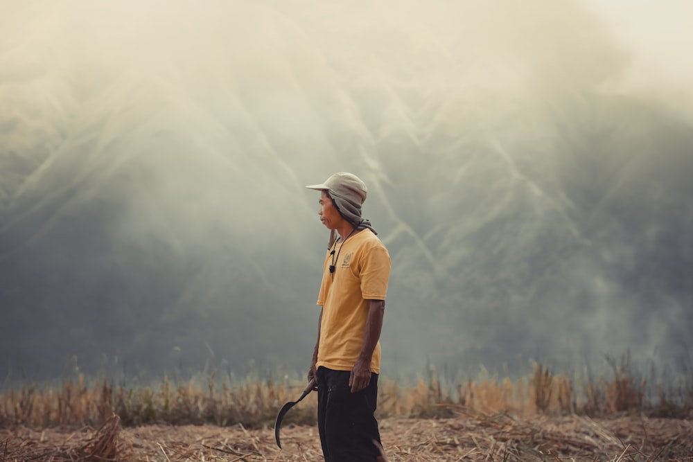 a man standing in a field with a hat on