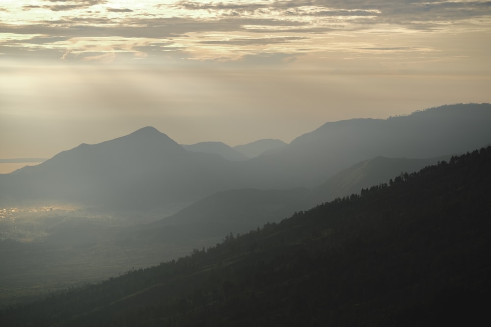 the sun shines through the clouds over the mountains