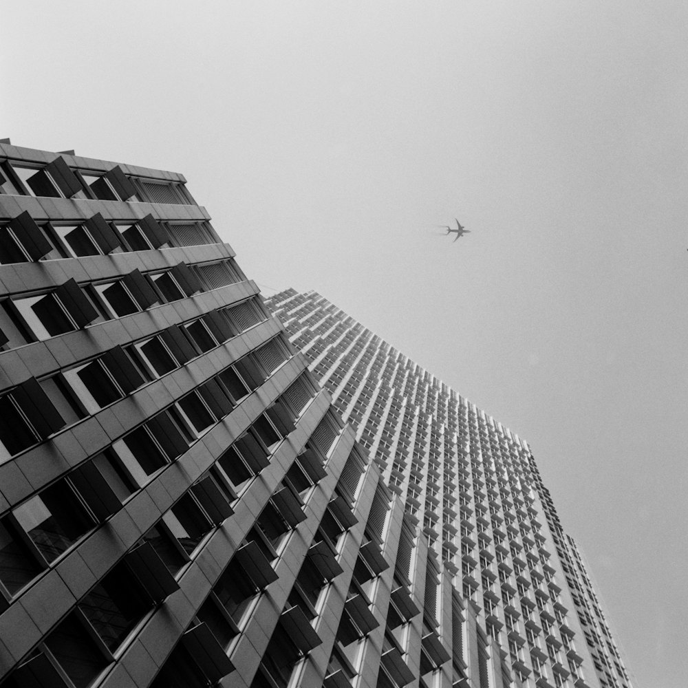 a plane flying in the sky over a tall building