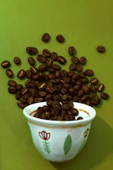 a cup filled with coffee beans on top of a green table