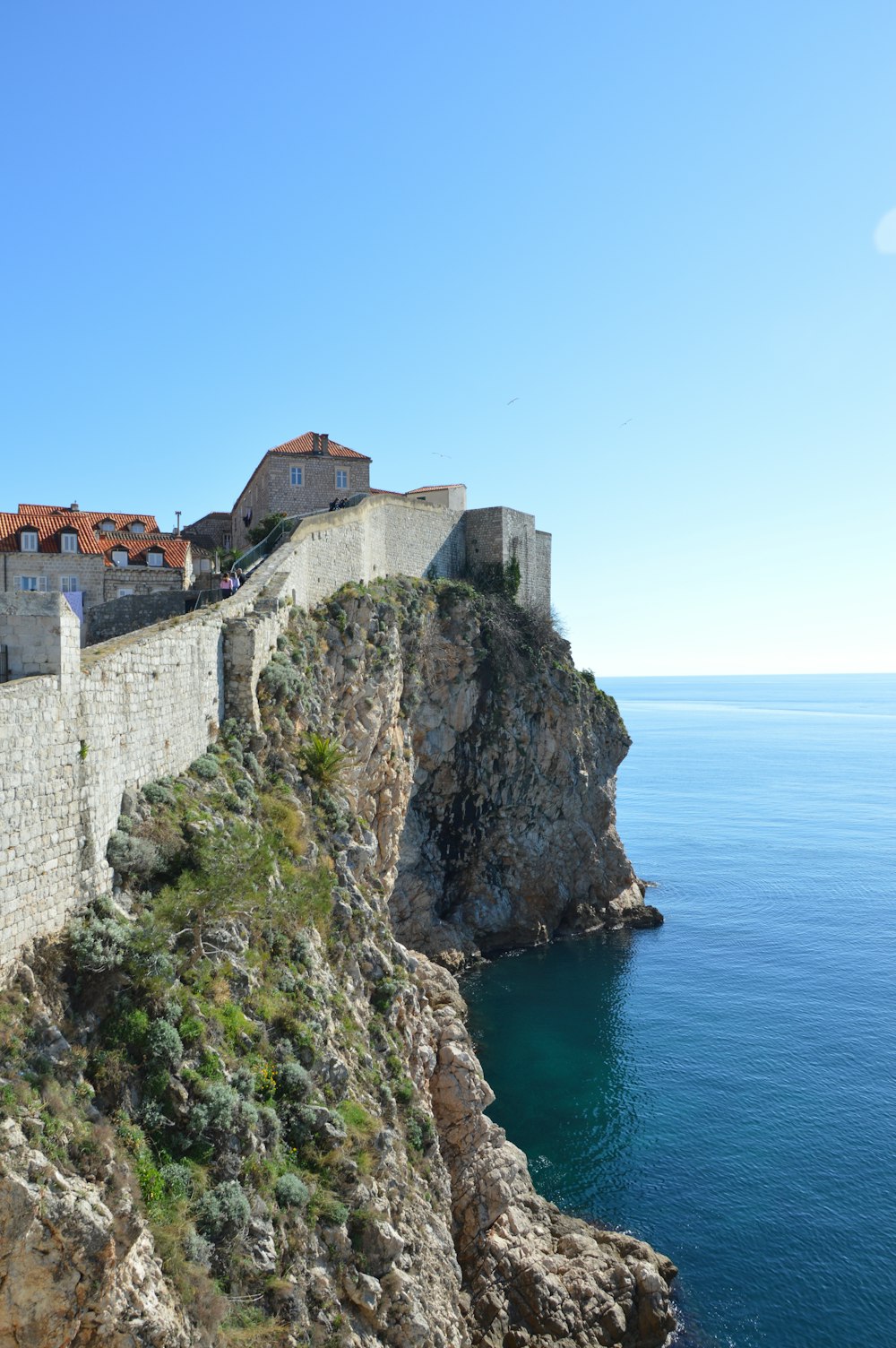 a large stone wall next to a body of water