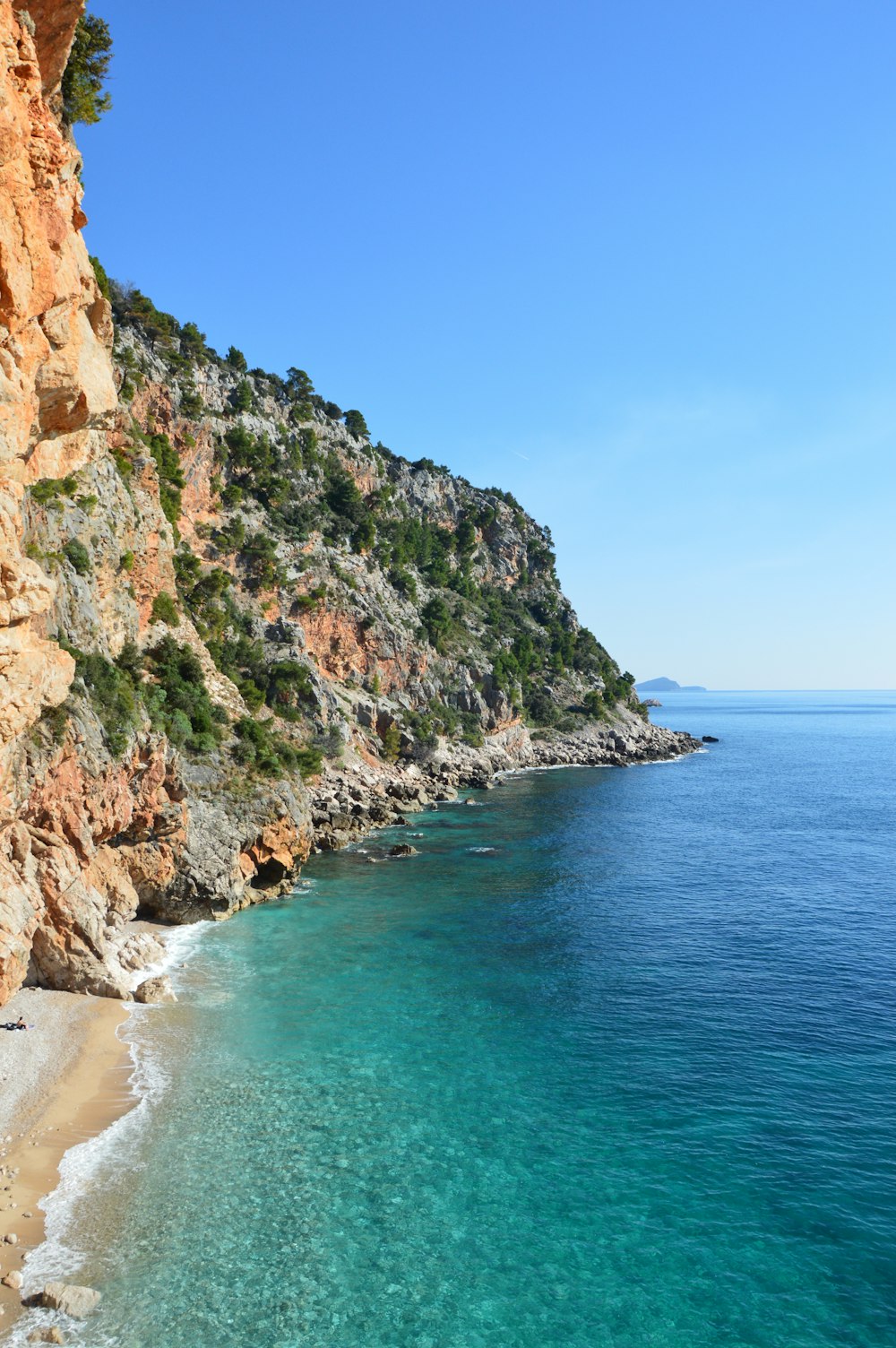 una spiaggia sabbiosa accanto a una scogliera con acqua cristallina