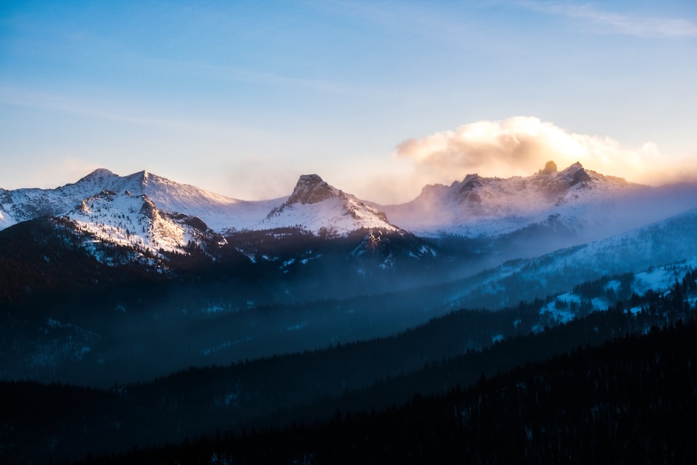 the mountains are covered in snow and clouds