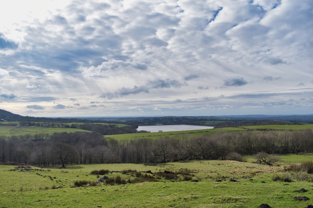 a green field with a lake in the distance