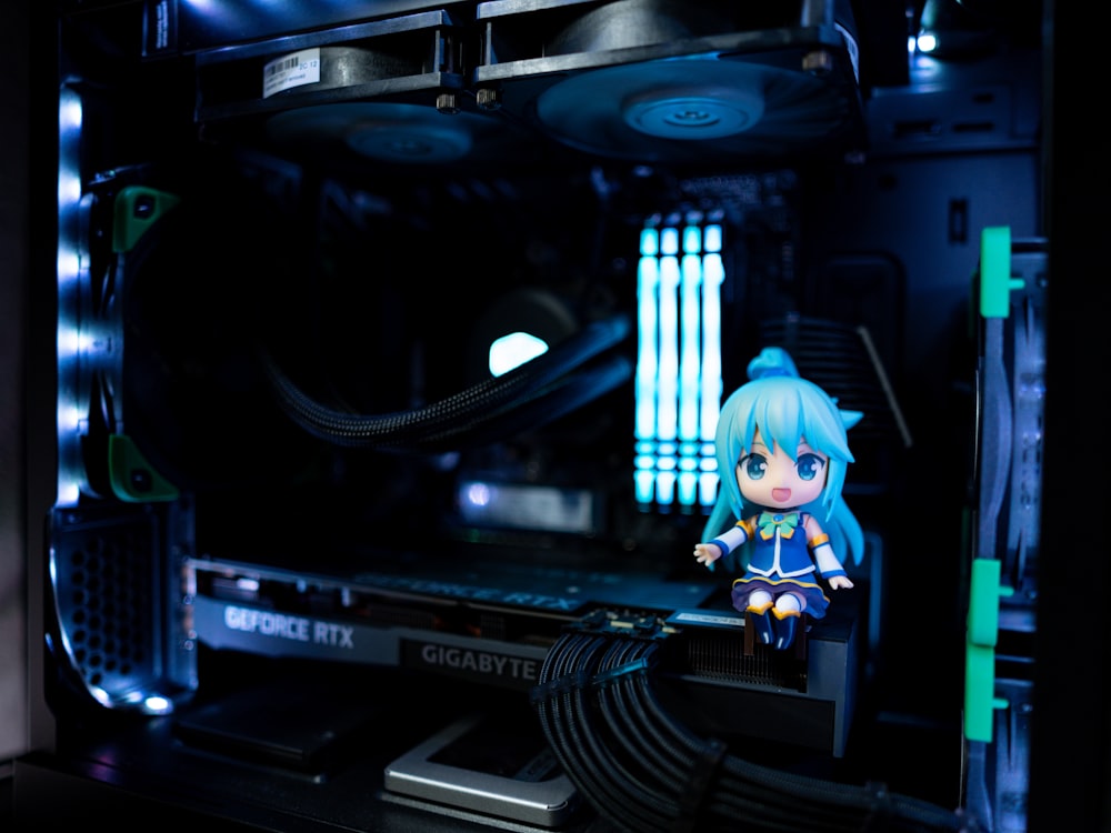 a small doll sitting on top of a computer