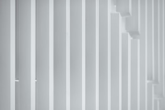 a man in a suit and tie standing in front of a white wall