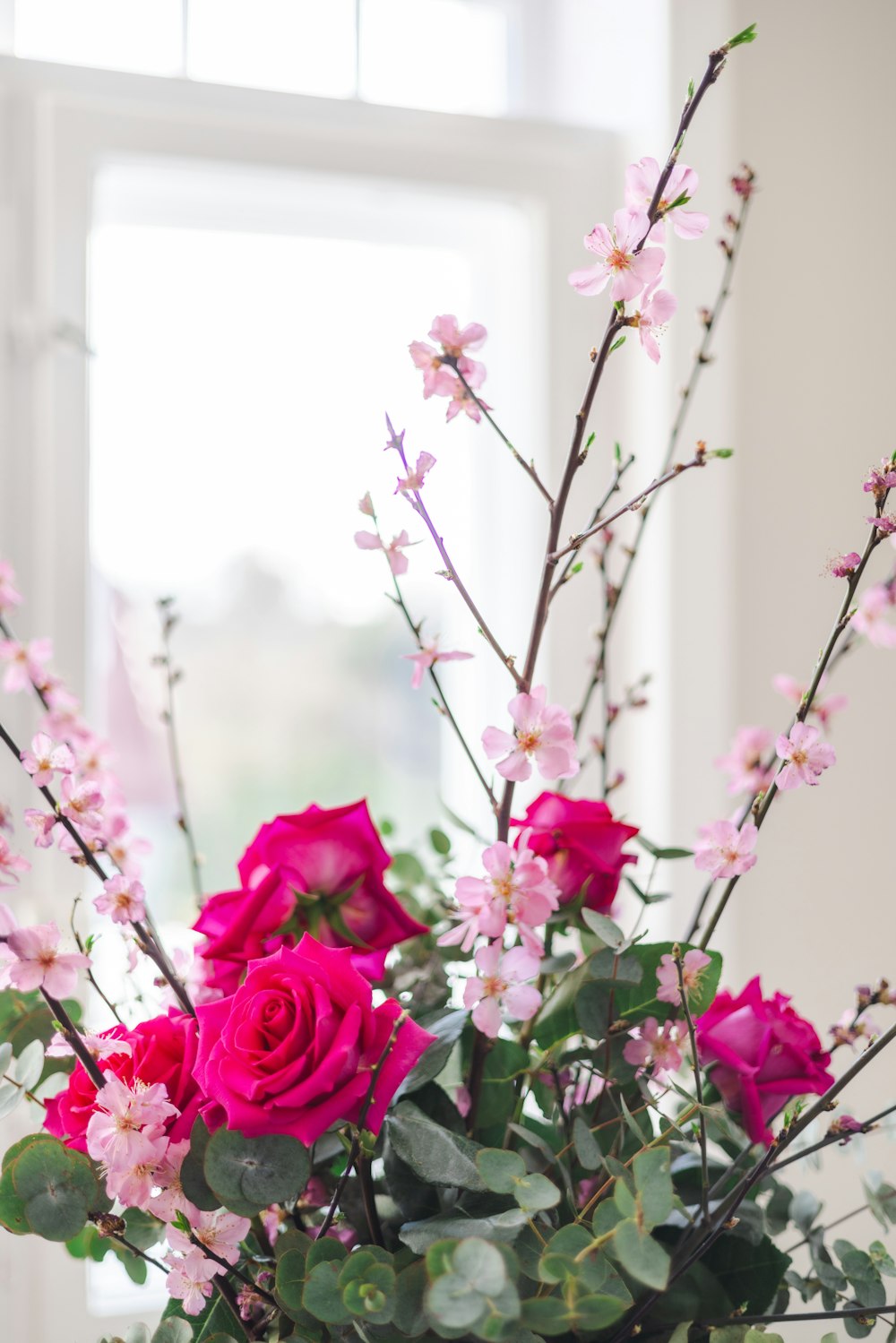 a vase filled with pink flowers next to a window