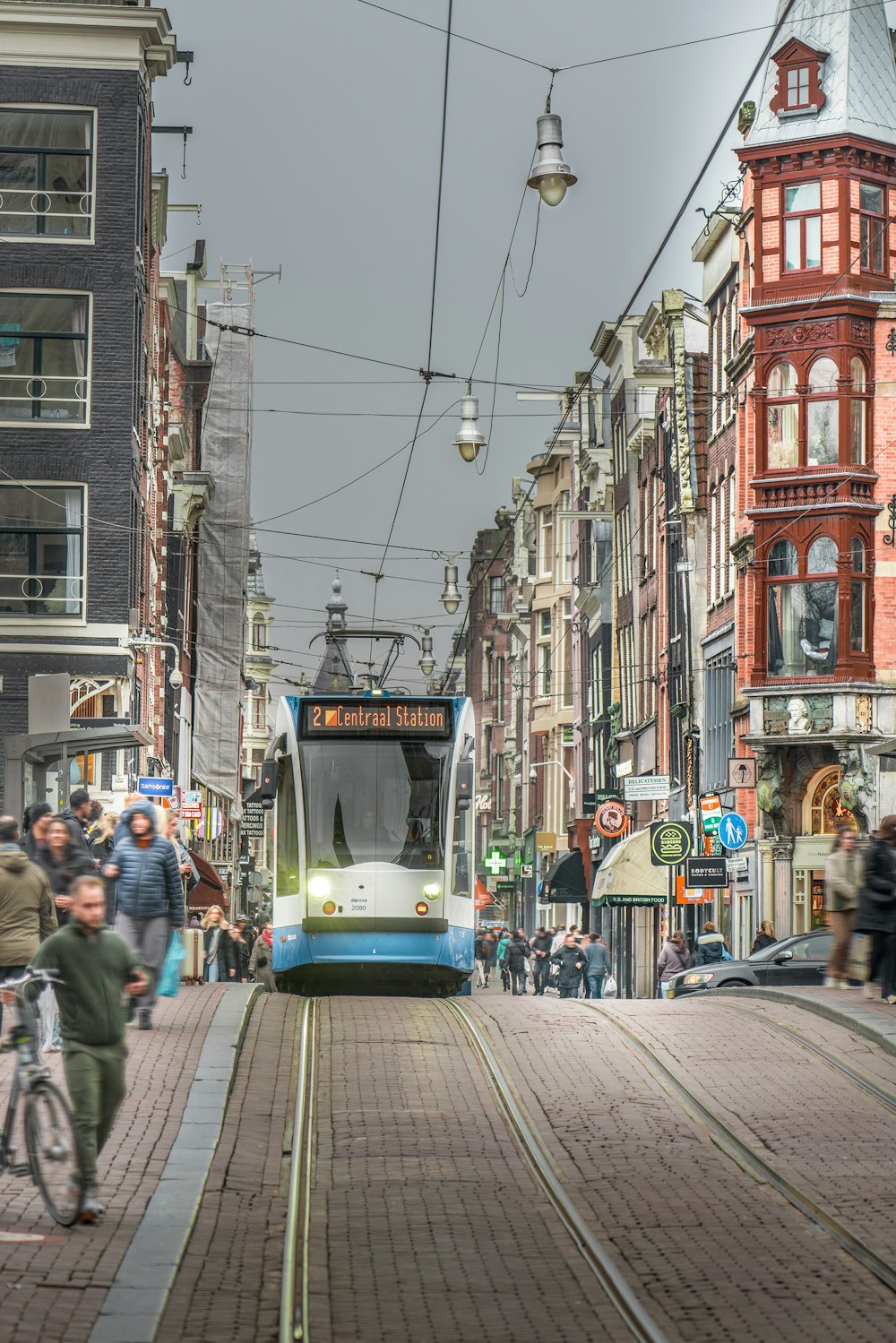 a blue and white train traveling down a street next to tall buildings