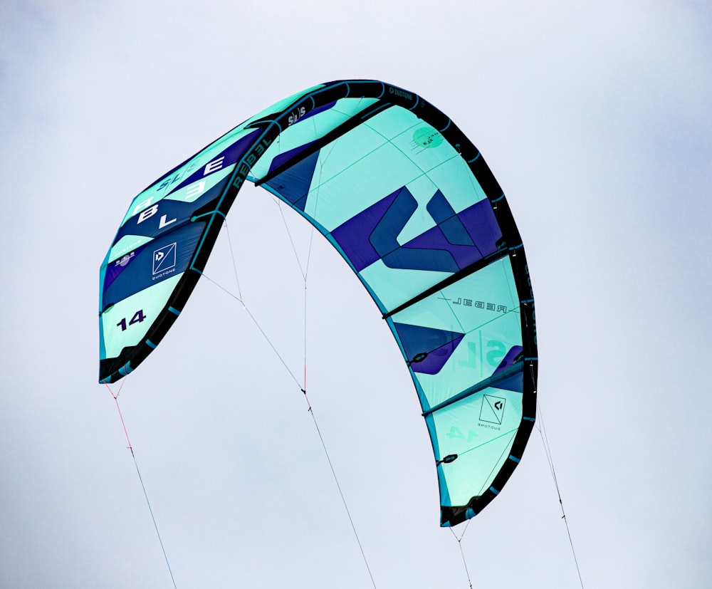 a blue and green kite flying in the sky