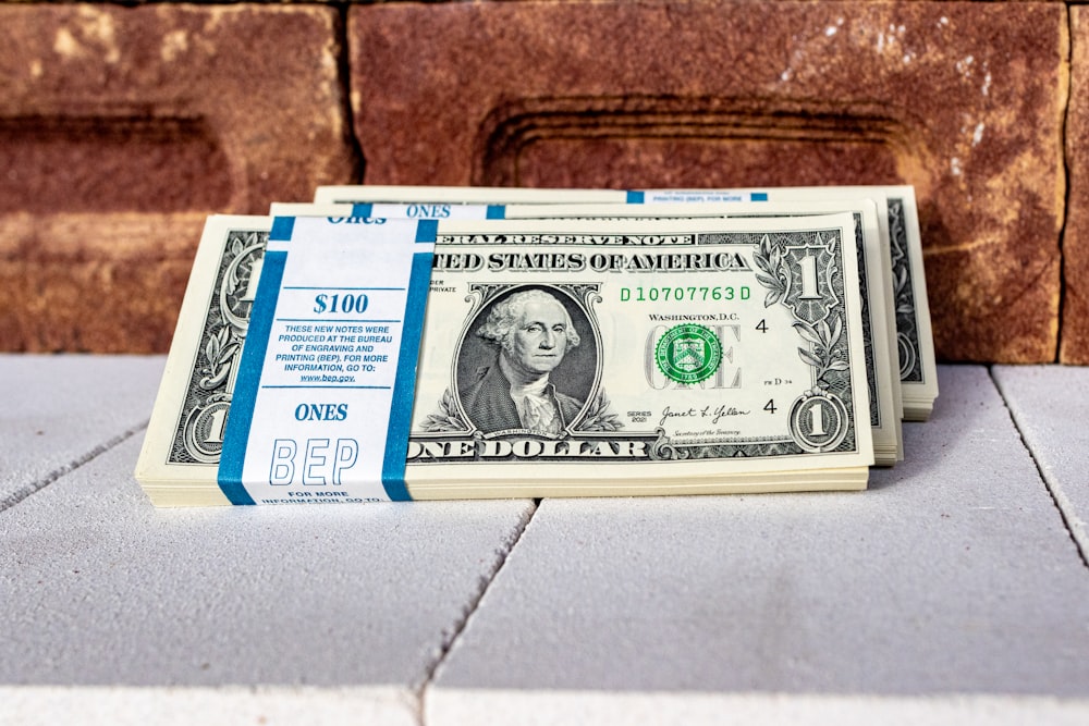 a stack of one dollar bills sitting on top of a counter