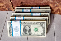 three stacks of one hundred dollar bills on a tile floor