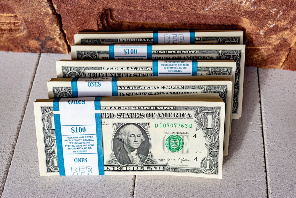 three stacks of one hundred dollar bills on a tile floor